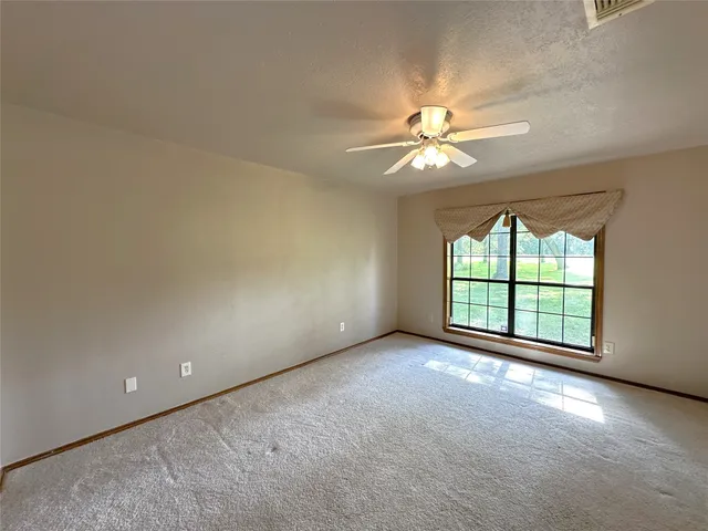 an empty room with windows and ceiling fan