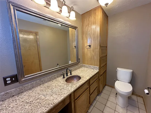 a bathroom with a granite countertop sink toilet and mirror