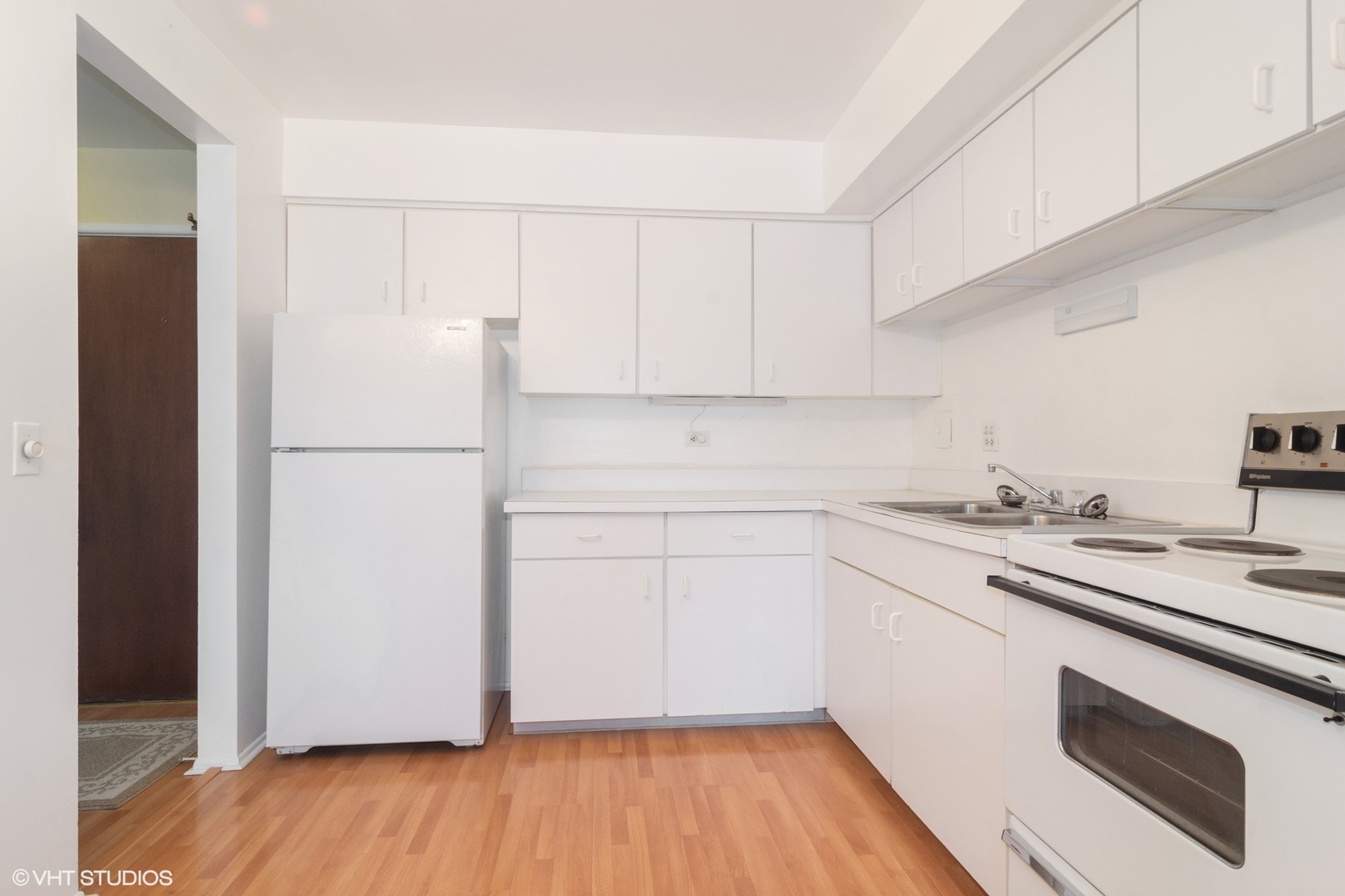 2407 East Brandenberry Court, Unit 1L Arlington Heights, IL 60004 - Photo 4 of 10 a kitchen with a sink a refrigerator and white cabinets