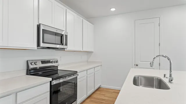 a kitchen with stainless steel appliances granite countertop a sink stove and microwave