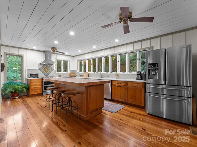 a kitchen with stainless steel appliances granite countertop a refrigerator a sink dishwasher a stove and white countertops with wooden floor