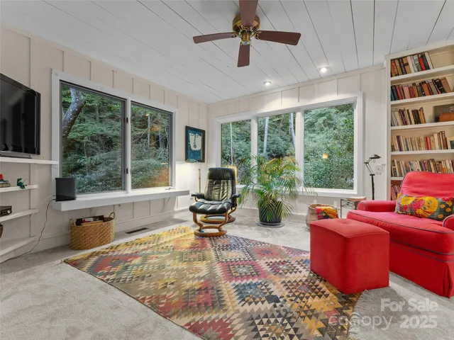 a living room with furniture a flat screen tv and a floor to ceiling window