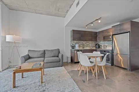 a kitchen with a dining table chairs and refrigerator