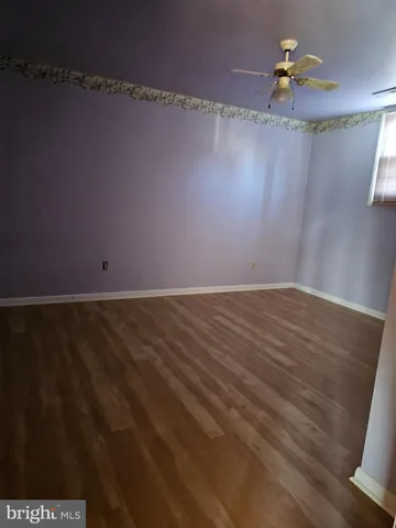 a view of a room with hardwood floor and a ceiling fan