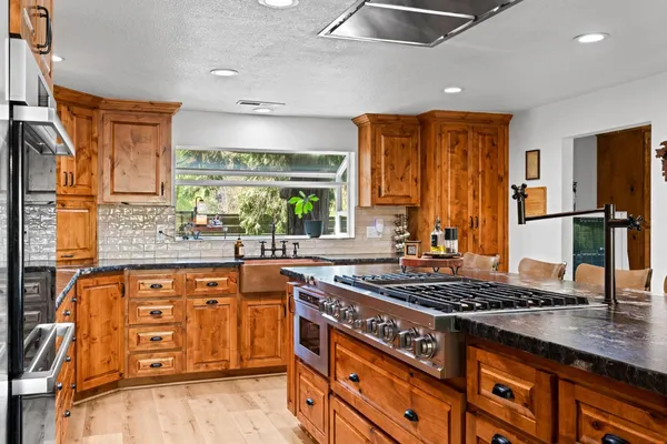 a kitchen with stainless steel appliances granite countertop a stove a sink and cabinets