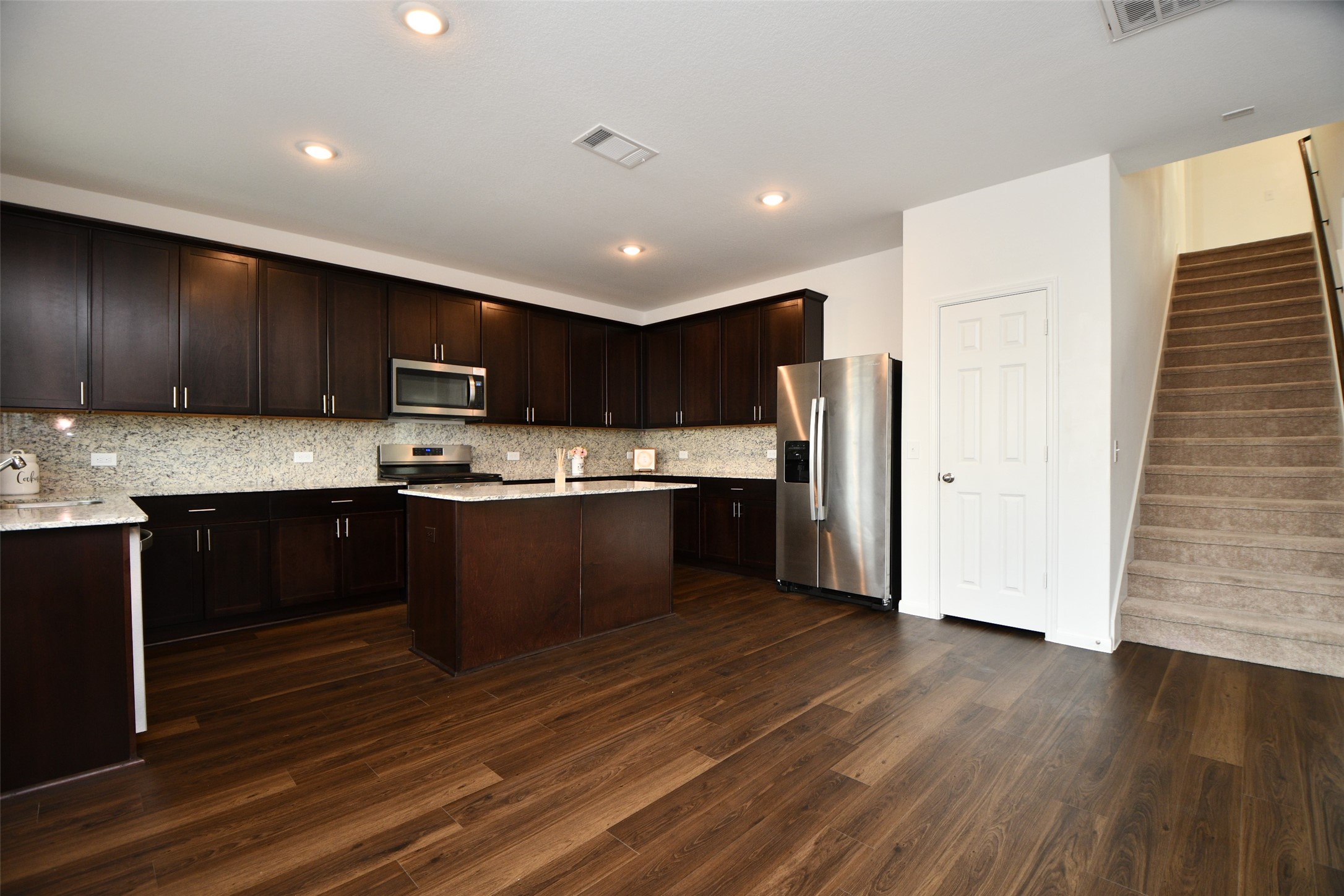 7329 Madison Commons Lane Houston, TX 77075 - Photo 12 of 22 a kitchen with kitchen island granite countertop wooden floors stainless steel appliances a sink and cabinets