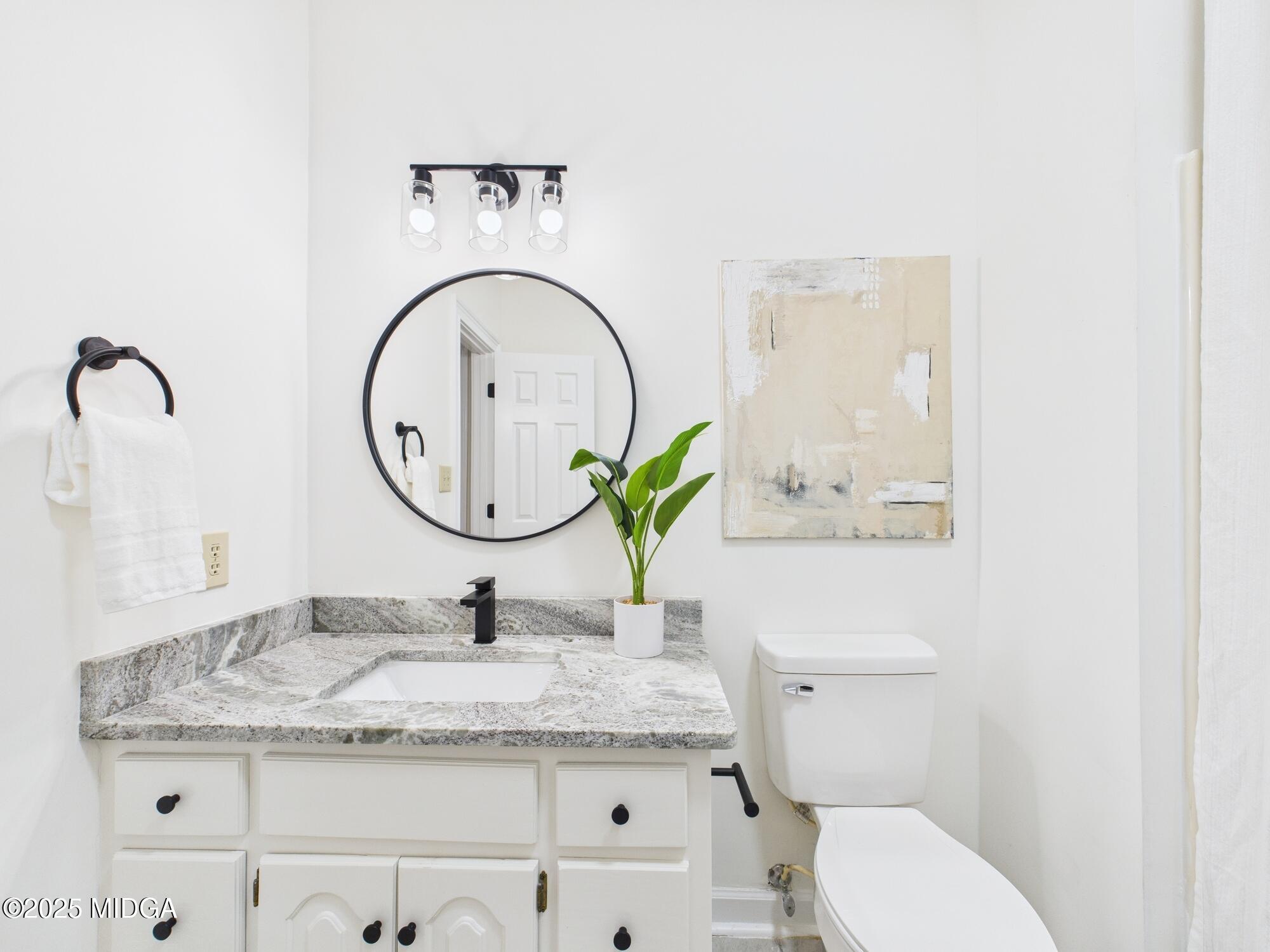 607 Chastain Place Macon, GA 31210 - Photo 28 of 63 a bathroom with a granite countertop toilet a sink and a mirror