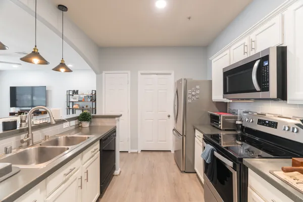 a kitchen with stainless steel appliances granite countertop a sink a stove a refrigerator a microwave oven with cabinets