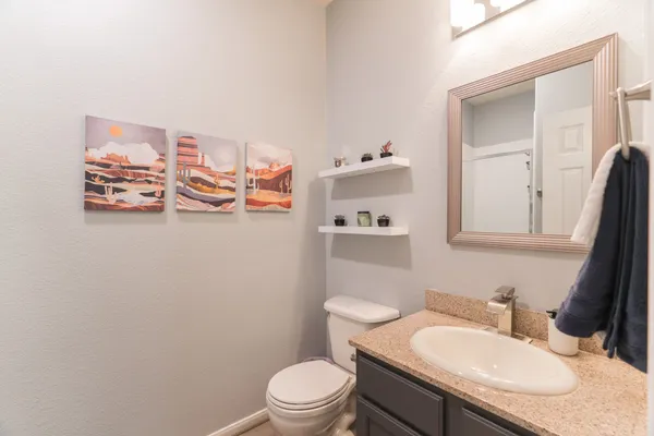 a bathroom with a granite countertop sink mirror vanity and toilet