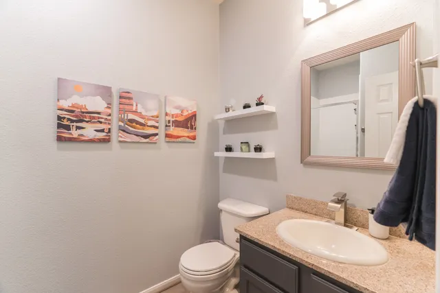 a bathroom with a granite countertop sink mirror vanity and toilet