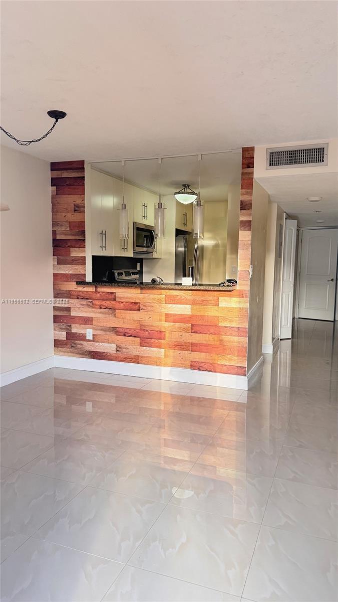 a view of empty room with kitchen and refrigerator