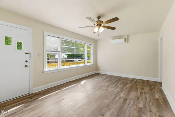 a view of an empty room with wooden floor and a window