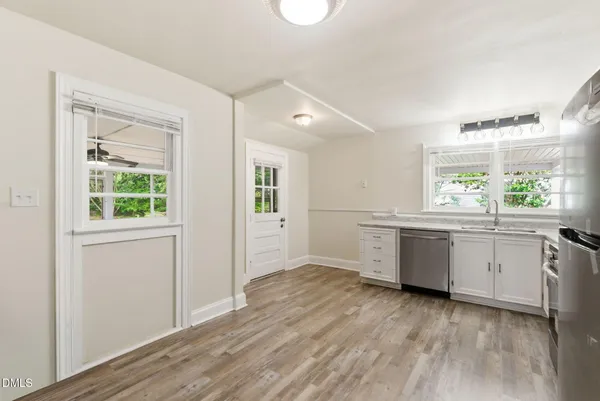 a kitchen with a white wooden cabinets and wooden floor