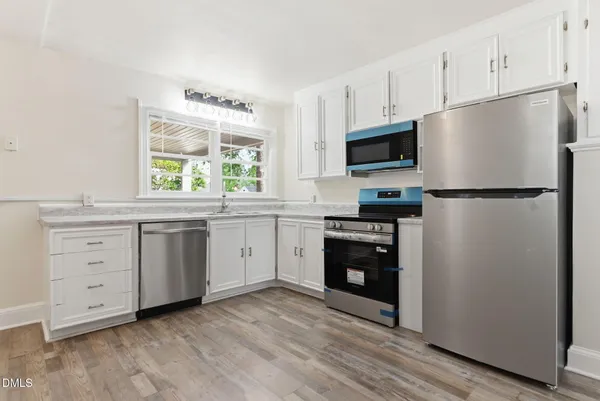 a kitchen with white cabinets white stainless steel appliances and refrigerator