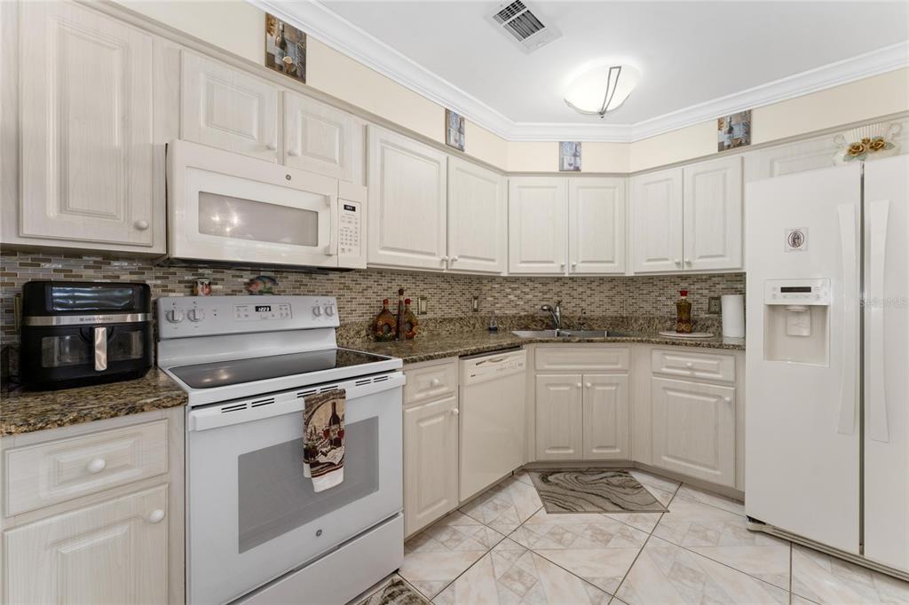 2779 Muscatello Street Orlando, FL 32837 - Photo 13 of 36 a kitchen with white cabinets and white appliances
