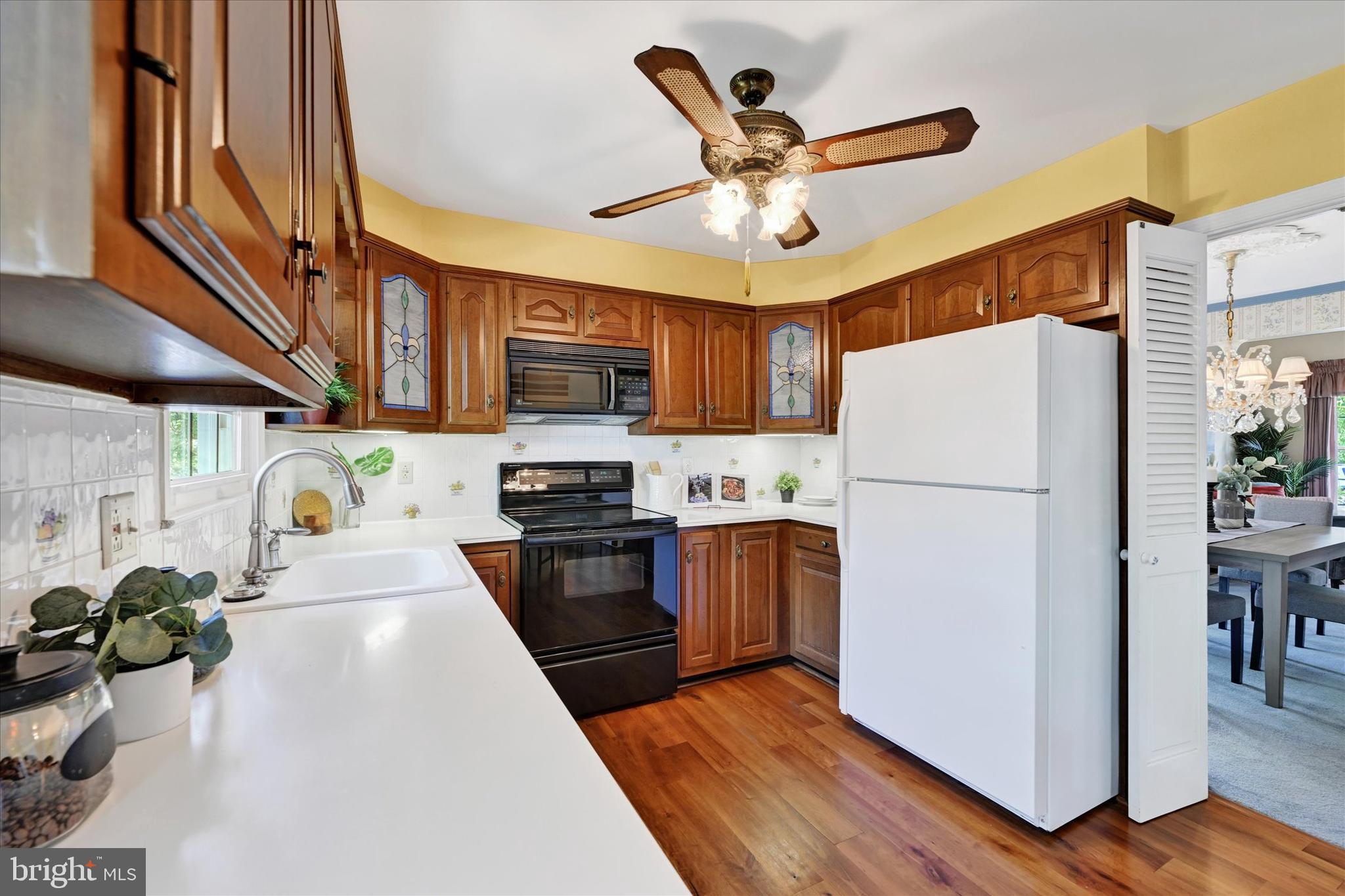 9115 Kilbride Road Baltimore, MD 21236 - Photo 14 of 61 a kitchen with stainless steel appliances granite countertop a refrigerator a stove top oven a sink a dining table and chairs with wooden floor