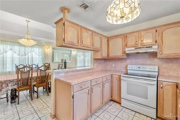 a kitchen with cabinets appliances and a chandelier