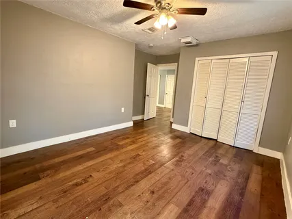 an empty room with wooden floor and ceiling fan