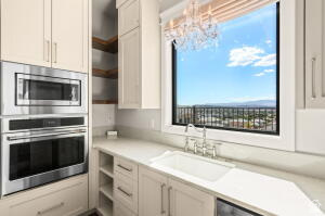 1141 East Lost Ridge Drive Washington, UT 84780 - Photo 40 of 108 Kitchen featuring stainless steel built-in microwave and oven, recessed shelving, neutral cabinetry, a single basin sink with a chrome faucet, and a large window with city and mountain scenery