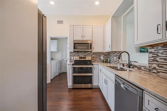 a kitchen with stainless steel appliances granite countertop a stove top oven a sink and dishwasher with wooden floor