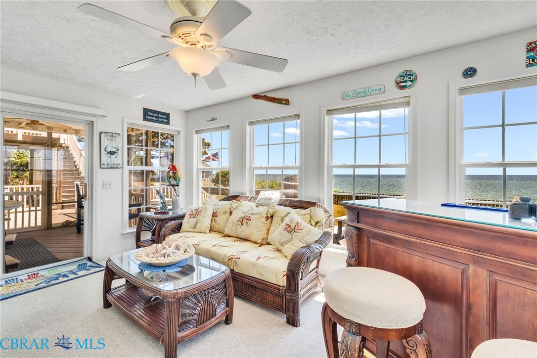 13 Leming Avenue Reedville, VA 22539 - Photo 21 of 50 Bright interior space featuring multiple windows, water scenery, a sliding glass door to an exterior deck, a ceiling fan, and built-in bar