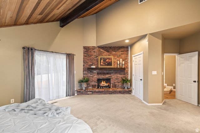460 Omni Point Road Central Valley, UT 84754 - Photo 36 of 101 Corner brick fireplace with a wood mantel, vaulted wood-plank ceiling with exposed beams, light-colored carpet, and sliding glass door