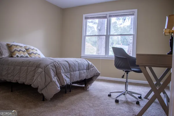 a bedroom with a bed a chair and a potted plant