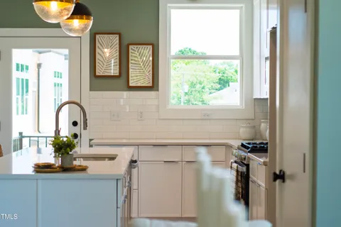 a room with stainless steel appliances kitchen island granite countertop furniture and a chandelier
