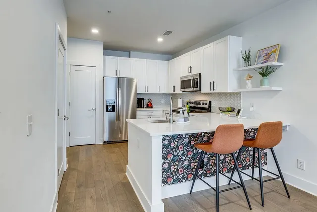 a kitchen with stainless steel appliances granite countertop a stove a refrigerator and a dining table with wooden floor