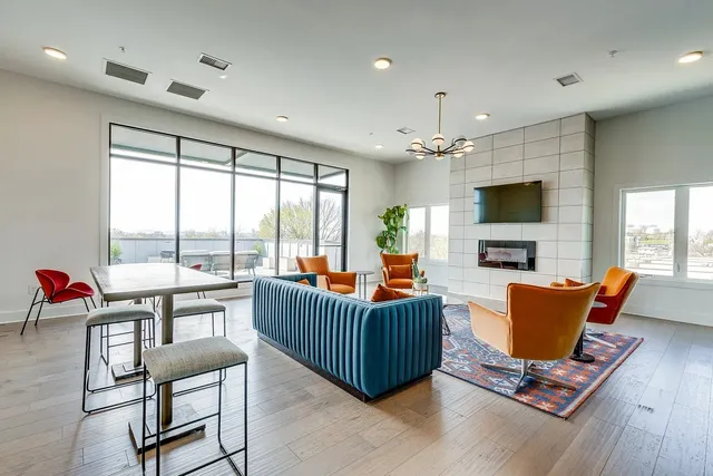 a living room with furniture a flat screen tv and a floor to ceiling window