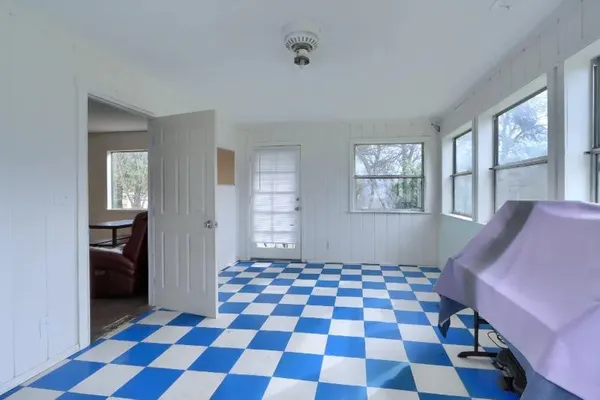 a living room with a black white checkered floor with a gaming machine and dining chair