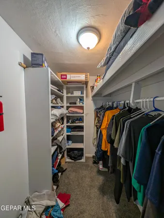a view of walk in closet with clothes and shoes