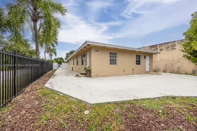 a view of a white house with a small yard and wooden fence