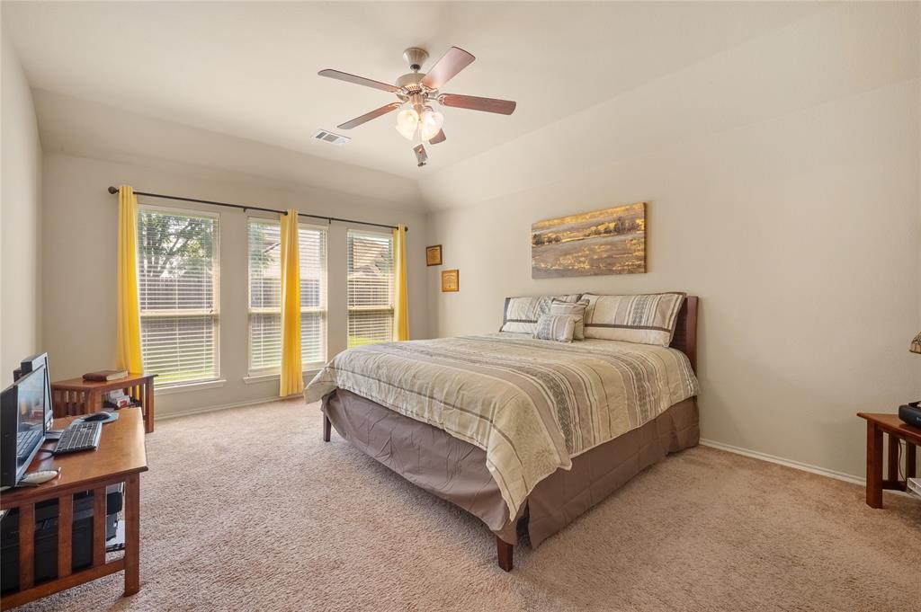 520 Rustic Oak Lane McKinney, TX 75072 - Photo 13 of 30 Spacious bedroom featuring vaulted ceilings, a ceiling fan with integrated lighting, and three tall windows providing natural illumination