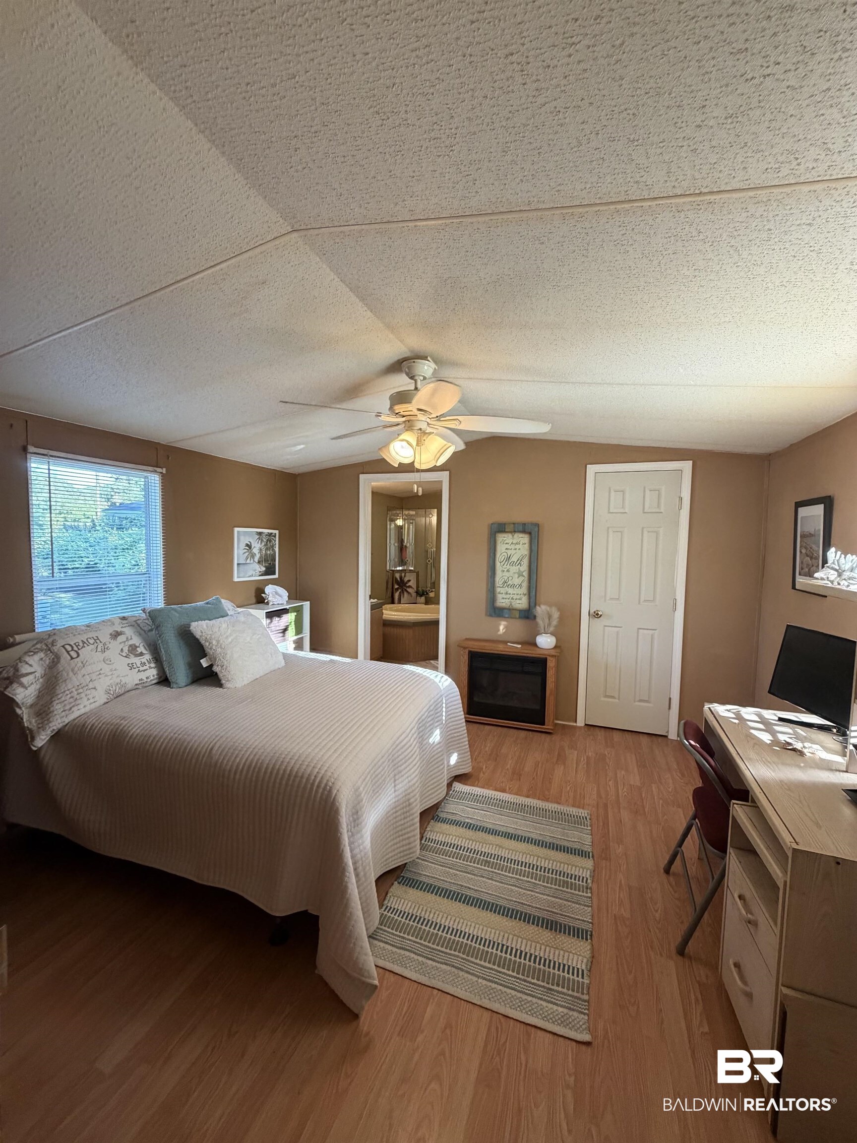 1125 Ridgewood Drive Lillian, AL 36549 - Photo 9 of 36 Spacious room featuring wood-finish flooring, a ceiling fan with integrated lighting, and a built-in electric fireplace