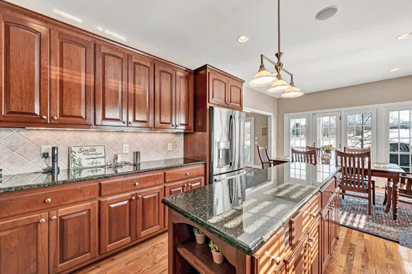 a kitchen with stainless steel appliances granite countertop a kitchen island a stove a sink dishwasher and microwave with wooden floor