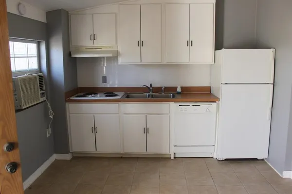 a kitchen with white cabinets and refrigerator