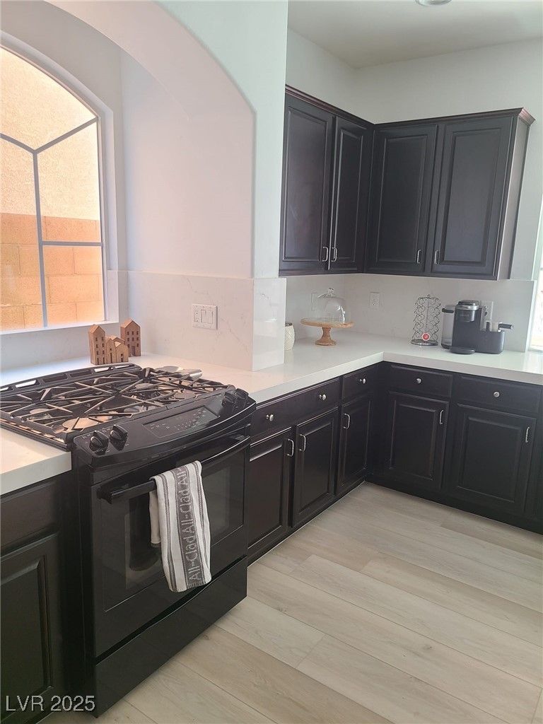 9629 Twin Rivers Court Las Vegas, NV 89139 - Photo 9 of 29 Kitchen featuring backsplash, light countertops, black range with gas cooktop, and light wood-type flooring