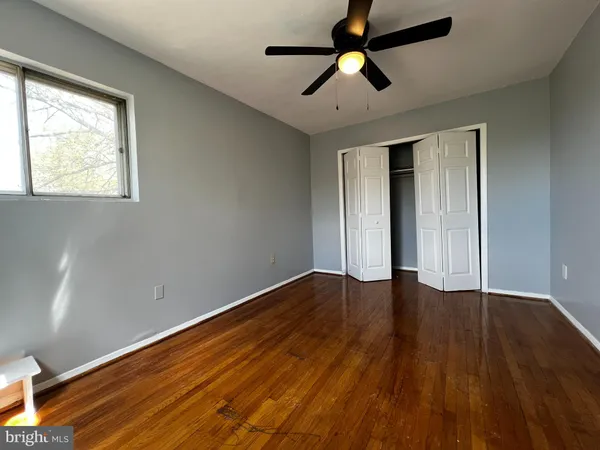 an empty room with wooden floor chandelier fan and windows