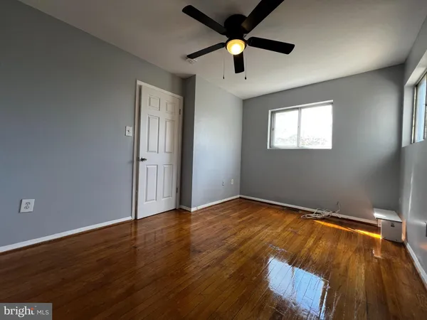 an empty room with wooden floor chandelier fan and windows