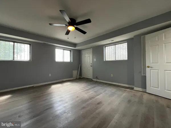 an empty room with wooden floor fan and windows