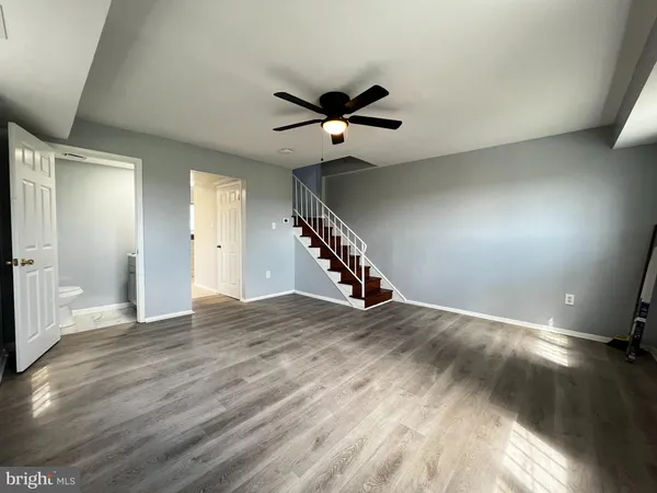 a view of an empty room with wooden floor stairs and a ceiling fan