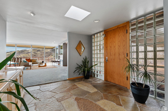 1856 Fort Canyon Road Alpine, UT 84004 - Photo 5 of 49 Foyer featuring flagstone flooring, a skylight, a wood-finish entry door, and glass block wall elements