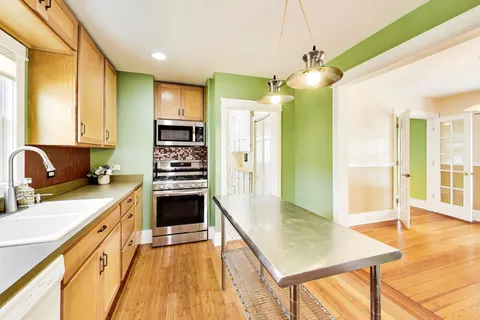 a kitchen with kitchen island a counter top space a sink stainless steel appliances and cabinets