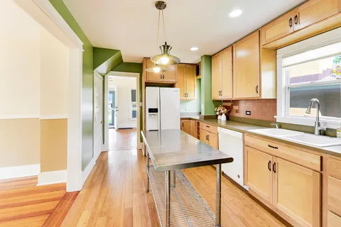 a kitchen with stainless steel appliances granite countertop a refrigerator a sink dishwasher a stove and white cabinets with wooden floor