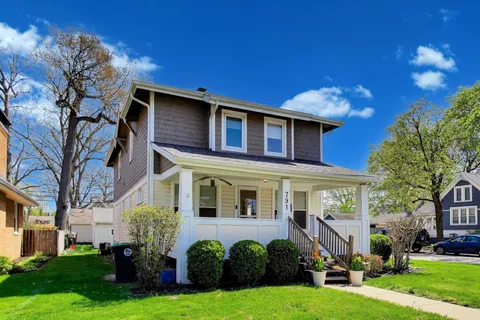 a front view of a house with a yard and potted plants and trees