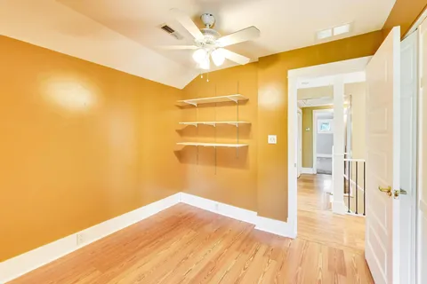 a view of a big room with wooden floor and a ceiling fan