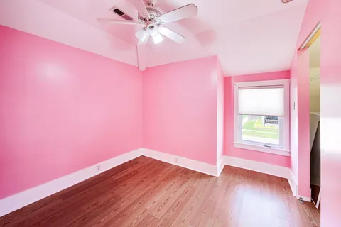 a view of empty room with wooden floor and fan