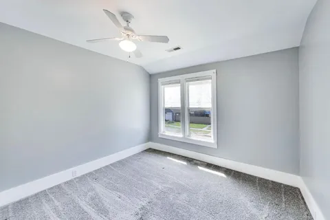 an empty room with windows and ceiling fan