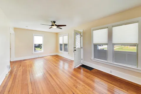 a view of an empty room with wooden floor and a window
